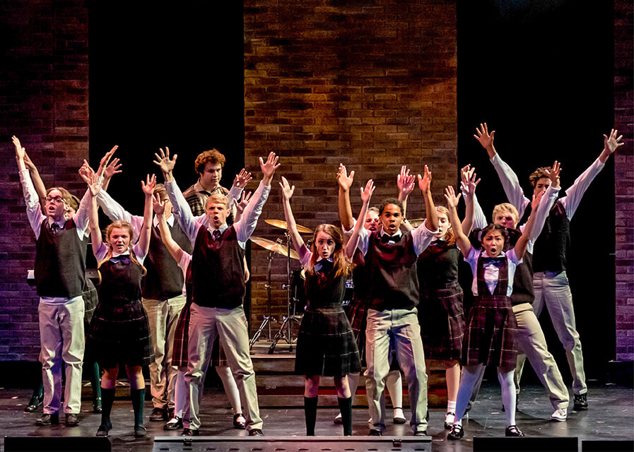 Students sing on stage during a performance